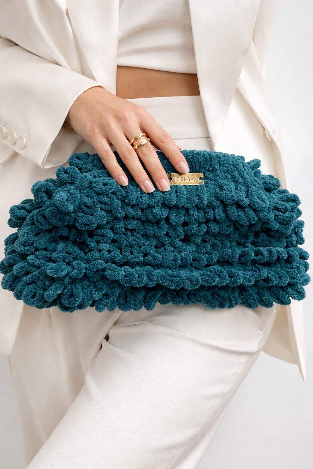 Teal clutch held by a person wearing a white outfit