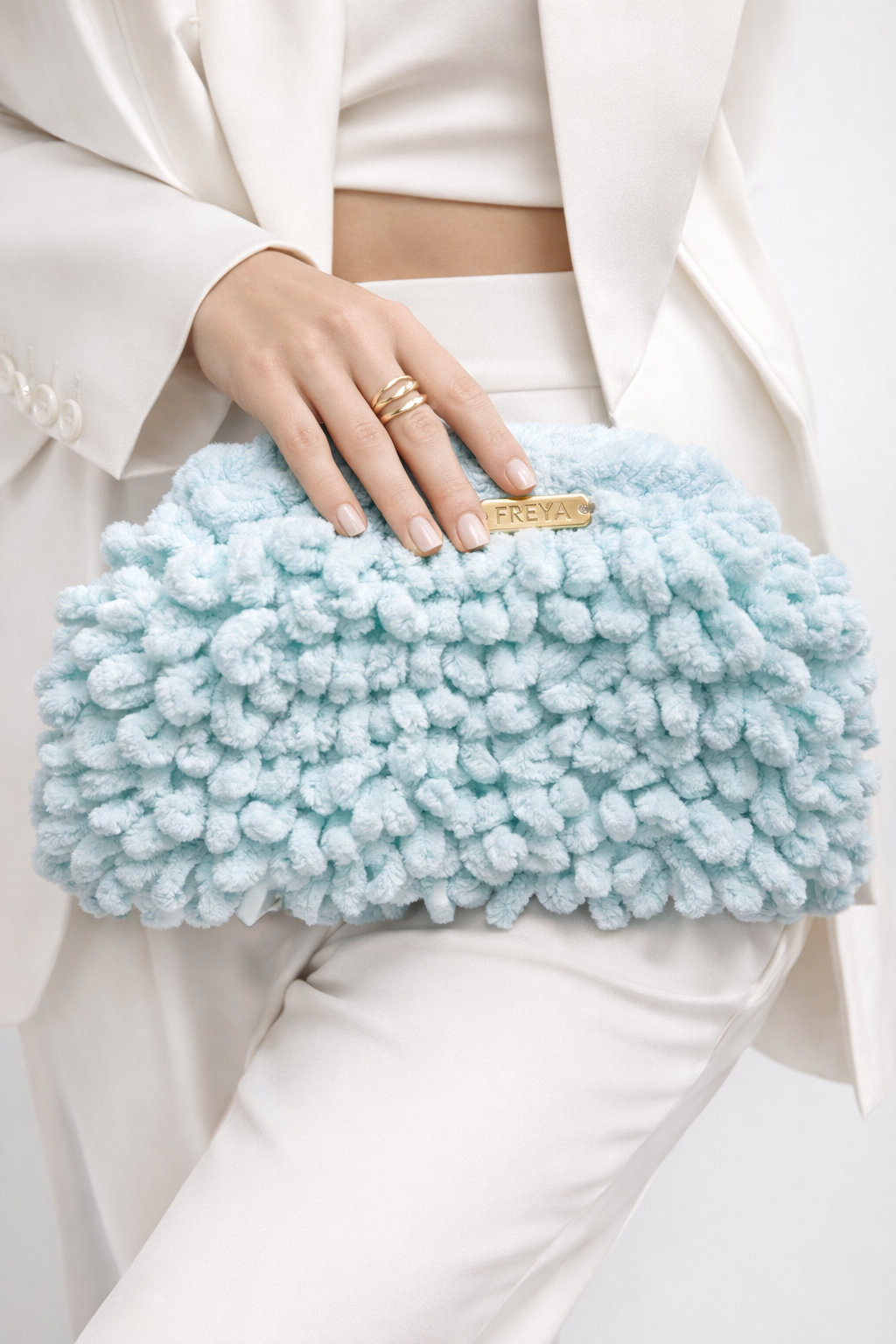 Light blue fluffy clutch held by a person wearing a white outfit.